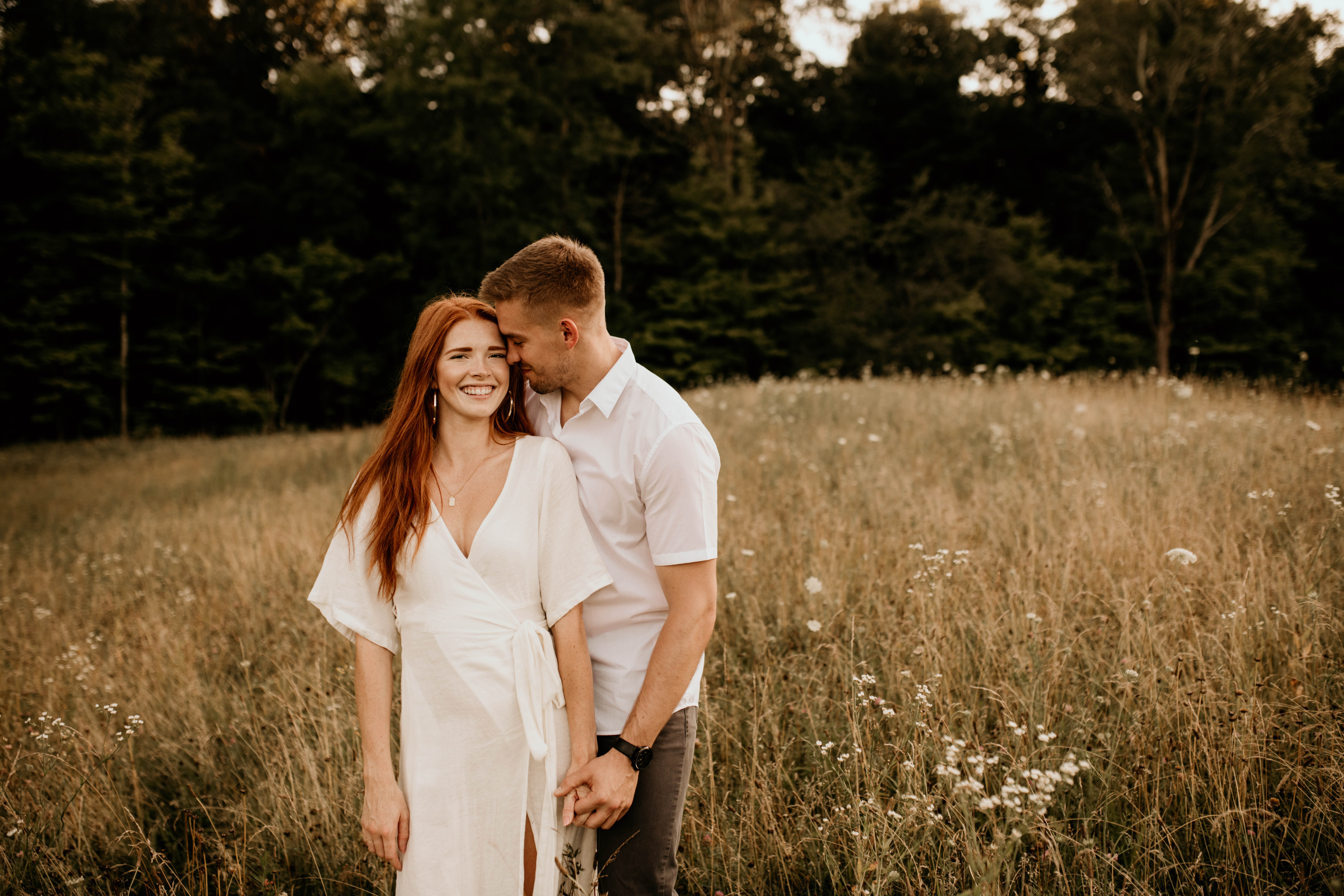 couple wearing all white in wildflower field. engagement portrait photo