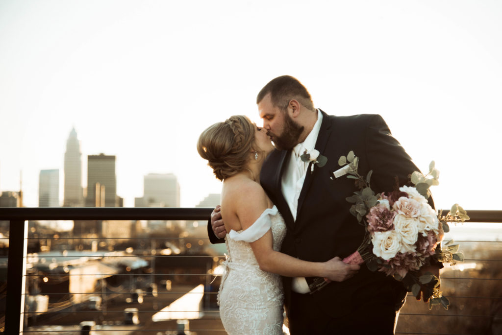 Bride and Groom kissing at Ariel International Center with Cleveland Skyline in background