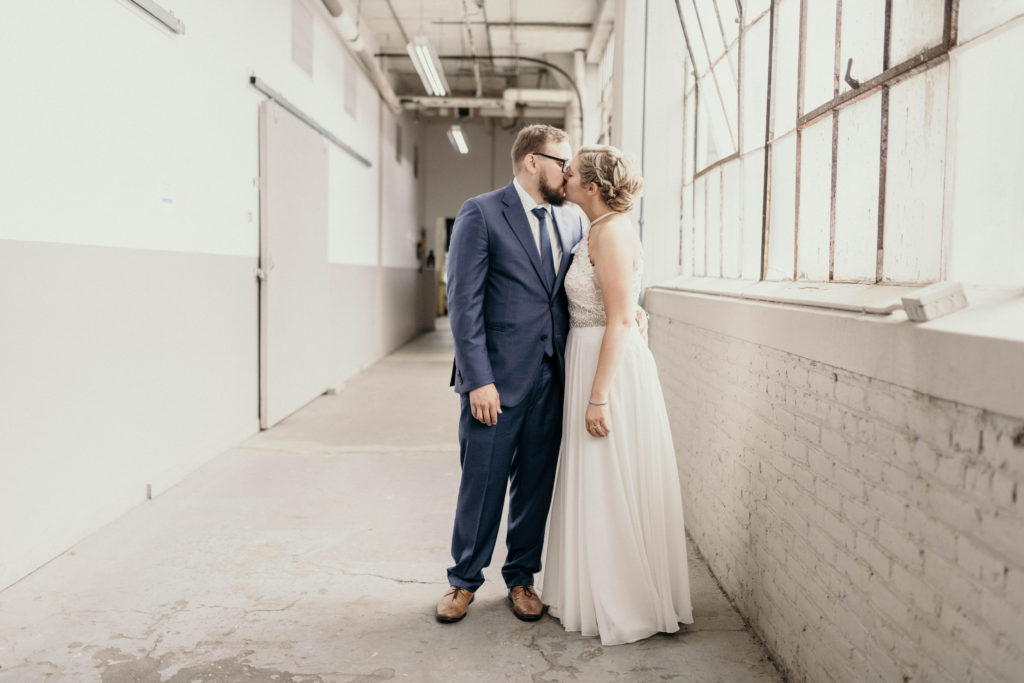 bride and groom kissing on wedding day in hallway at lake erie building
