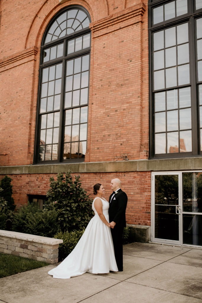 Bride and Groom holding hands against brick wall