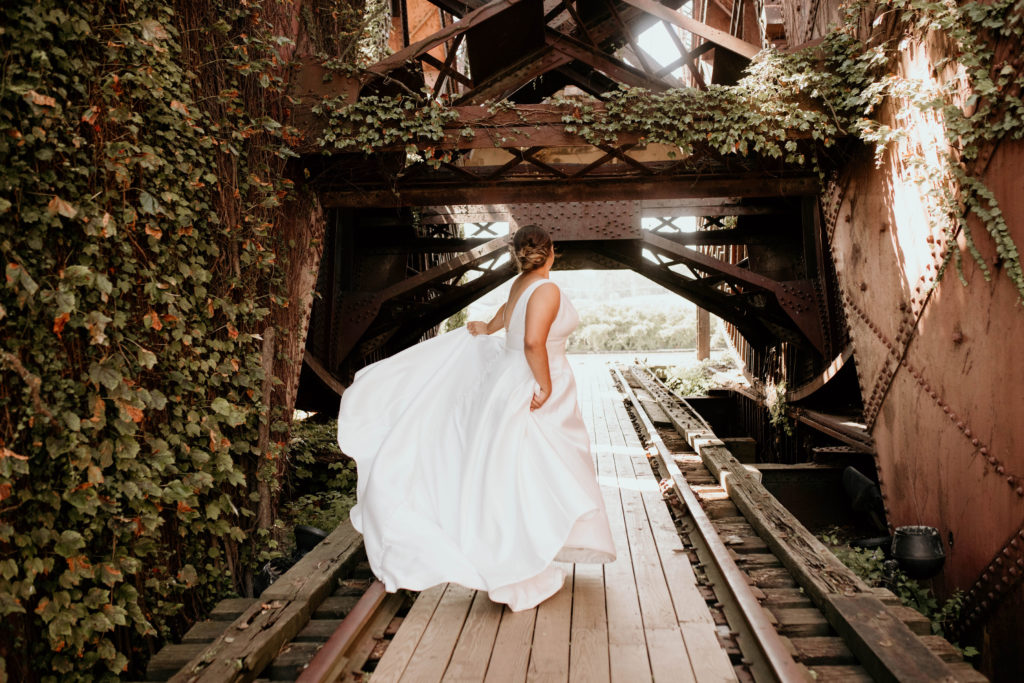 bride standing on bridge spinning in flowy dress
