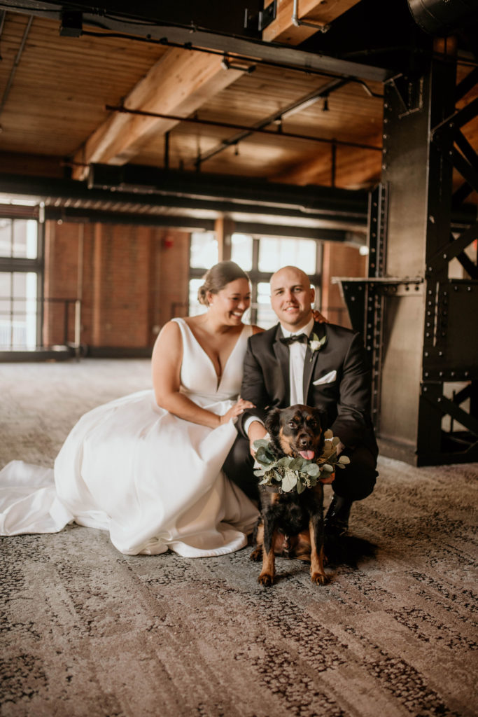 bride groom and dog smiling at camera at industrial wedding venue