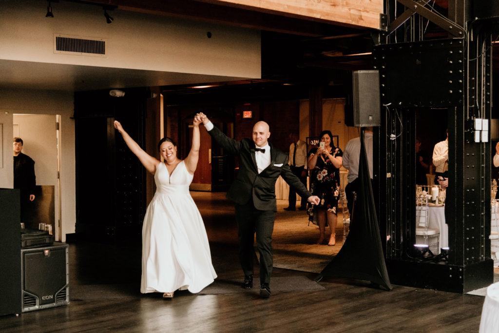 bride and groom walking in with hands up for first announcement