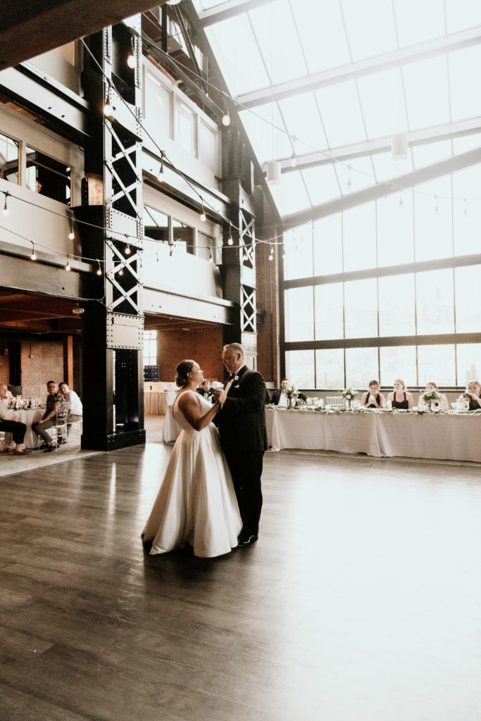 bride and groom dancing first dance at industrial venue