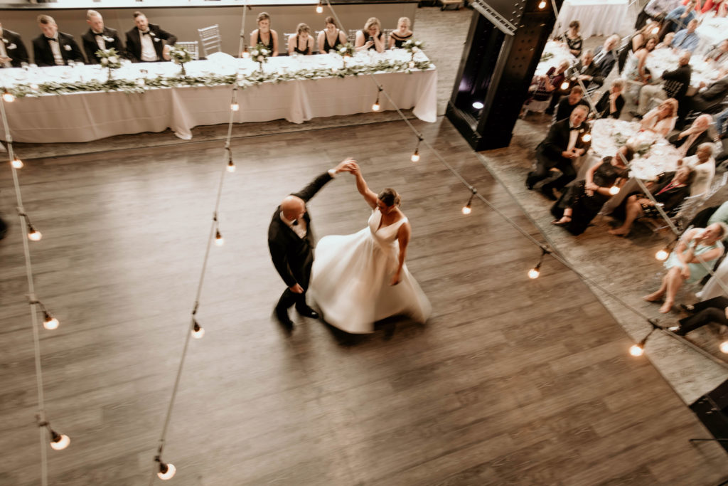 bride and groom dancing first dance under hanging lights