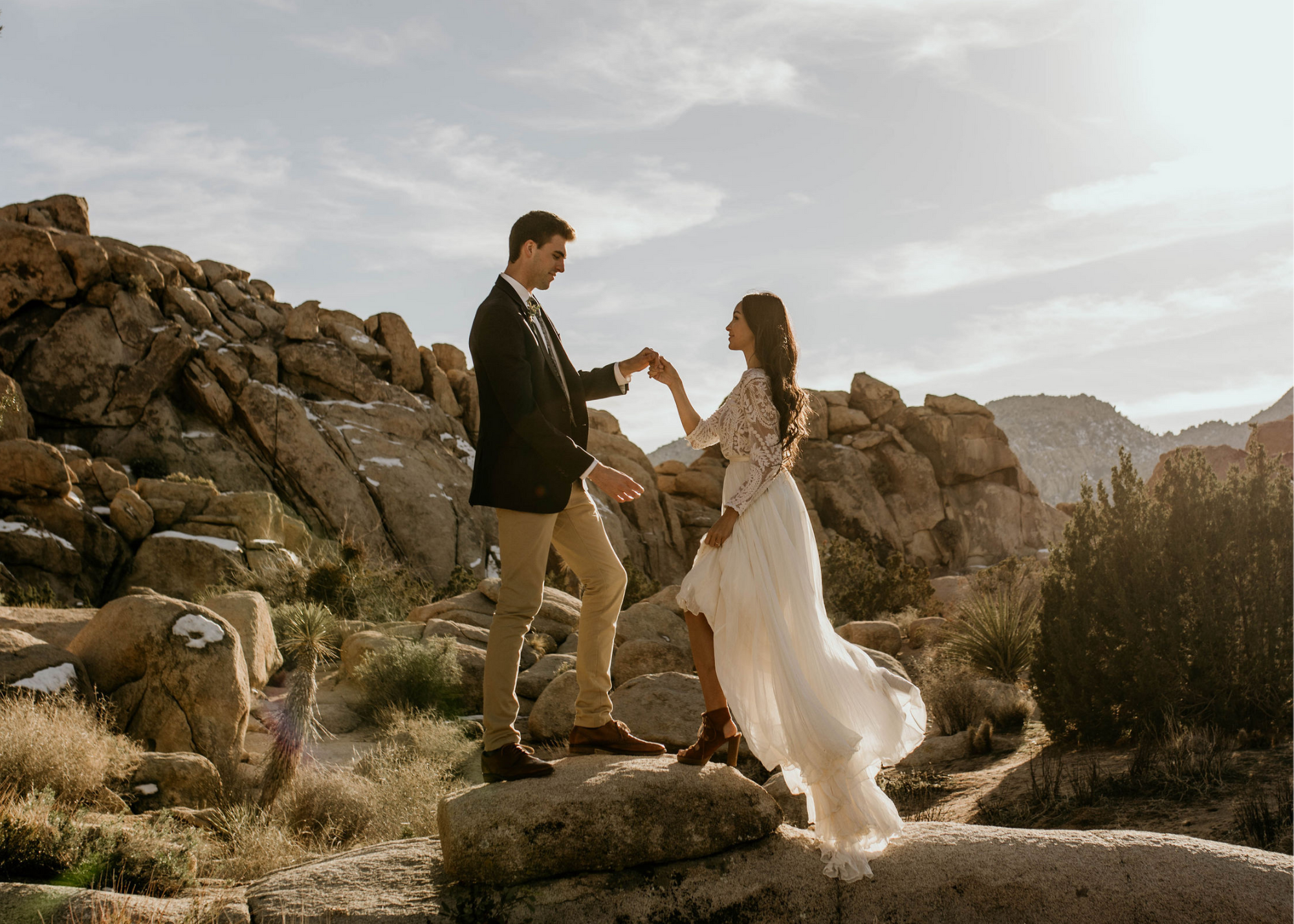 couple holding hands standing on rocks in desert, joshua tree national park, elopement getting married, wedding day