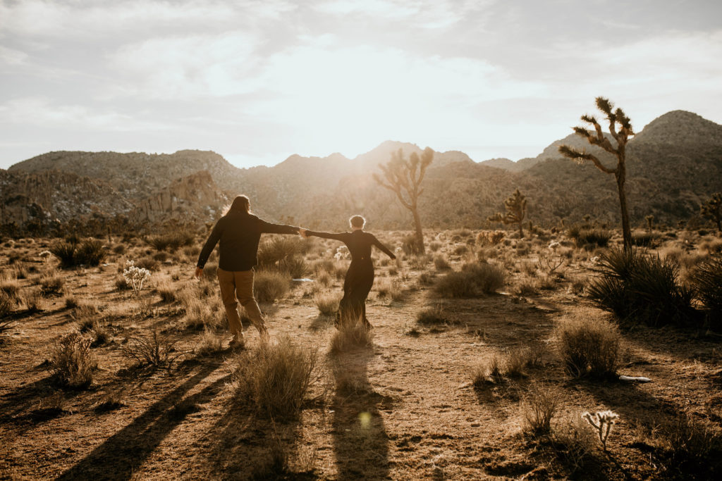 boho bride and groom holding hands adventuring elopement in joshua tree national park